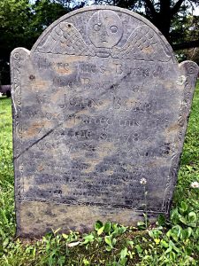 Colonial gravestone with a "deaths head" skull symbol at the top.