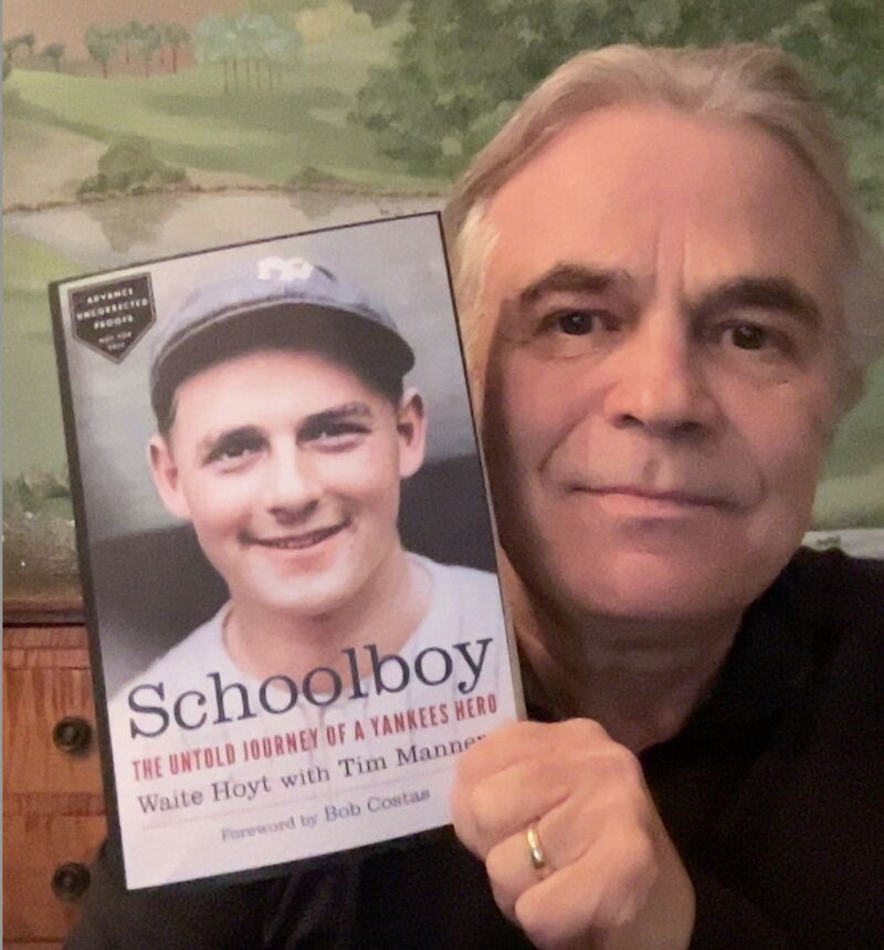 Author Tim Manners holds up book titled"Schoolboy"