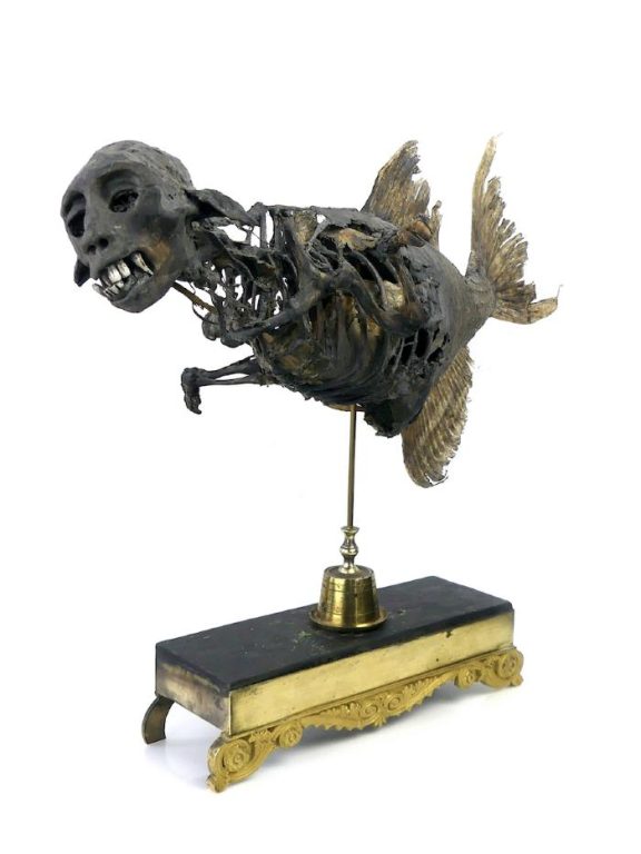 Mummified mermaid figure on a gold stand